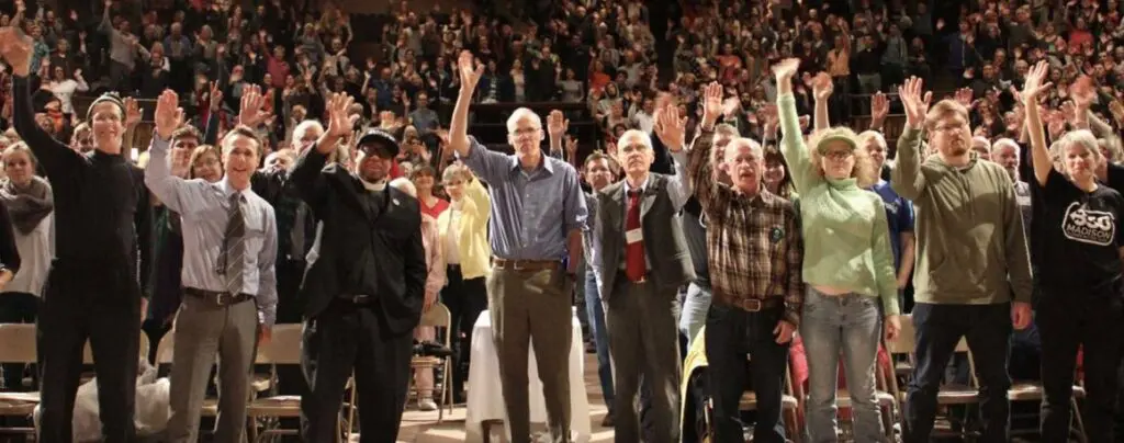 Large group of people raise their hands