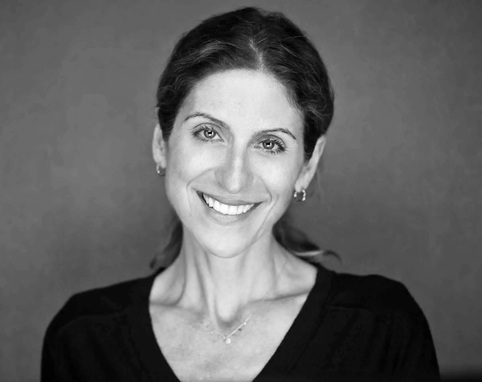 Smiling woman with dark hair and a necklace.